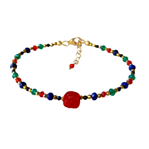 A small carved red agate flower is the centerpiece of a bracelet with blue lapis lazuli, green onyx, and orange carnelian roundel beads interspersed with smaller gold and black beads