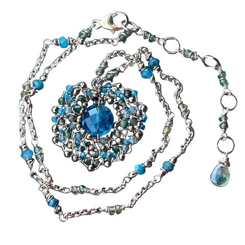 Necklace with blue gemstone and chain on a textured blue background