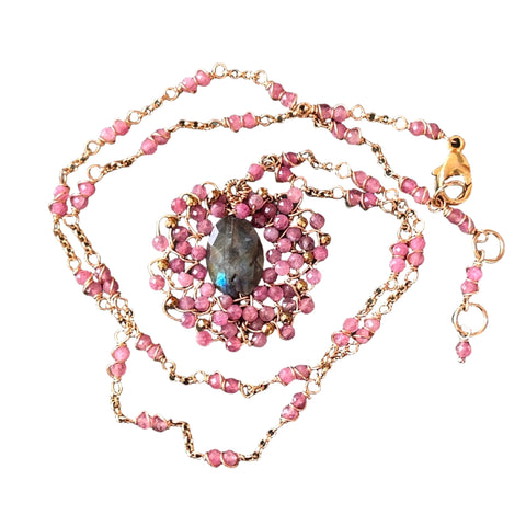Necklace with pink beads and gold chain on a textured surface