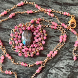 Necklace with pink beads and a central stone on a dark surface