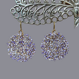 Light and dark tiny cut lavender zircon beads woven in circle earrings on gray background dancing amulets magical jewelry one of a kind 